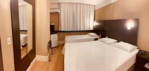Una habitación de hotel con dos camas y un espejo. en SJ Business - San Juan São Paulo, en São Paulo 51 fotos más