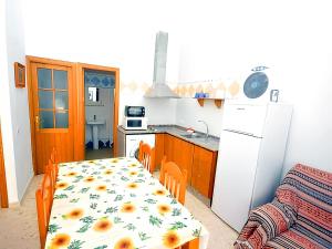 een keuken met een tafel en een witte koelkast bij Apartamentos Noria Familias y Parejas Gold in Conil de la Frontera