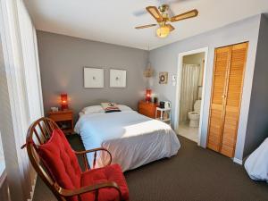 a bedroom with a bed and a chair at Les Petits Studios du bord de l'eau in Saint-Joseph-de-la-Rive