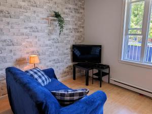 a living room with a blue couch and a tv at Les Petits Studios du bord de l'eau in Saint-Joseph-de-la-Rive