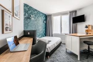 une chambre d'hôtel avec un ordinateur portable sur un bureau dans l'établissement Le Parc 42 Saint-Etienne, à Saint-Étienne