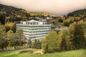 un grand bâtiment blanc sur une colline plantée d'arbres dans l'établissement Aparthotel - Apartament BiałaPerła, à Sienna