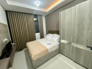 a small bedroom with a bed and a television at Cozy Studio Unit @Ciputra World Surabaya in Surabaya +13 photos