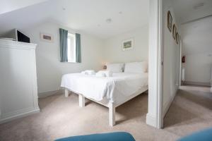 a white bedroom with a white bed and a window at Neptune House in Wells next the Sea