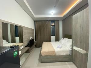 um quarto de hotel com uma cama e um espelho em Cozy Studio Unit @Ciputra World Surabaya em Surabaya