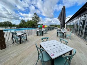 uma fila de mesas e cadeiras num deque em Spring View Hot tub Lodge em South Cerney