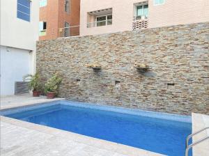 a swimming pool in front of a brick wall at Hotel Continental Plaza Barranquilla in Barranquilla