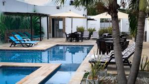 a swimming pool with chairs and a table and an umbrella at Hotel Bella Isa in La Dorada