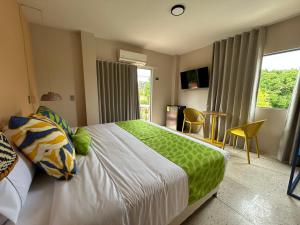Un dormitorio con una cama verde y blanca y una ventana en Del Trópico sopetrán en Sopetran
