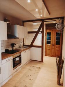 uma cozinha com armários brancos e uma porta aberta em Landhausstil Familienferienwohnung Florentine em Bad Klosterlausnitz