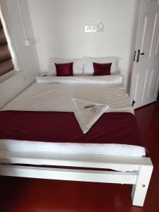 a white bed with red pillows in a bedroom at Tripsea Beach Villa in Alleppey