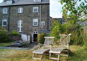dos sillas sentadas en el patio de una casa en Parrog Beach House - Sleeps 12, en Pembrokeshire
