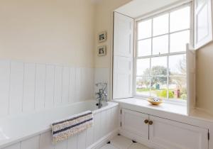 Un baño blanco con bañera y ventana. en Parrog Beach House - Sleeps 12, en Pembrokeshire 49 fotos más