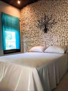 a bedroom with a large white bed with a stone wall at Villa Patara in Marechal Deodoro