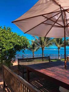 - un banc en bois avec un parasol sur la plage dans l'établissement Villa Patara, à Marechal Deodoro
