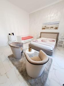 a bedroom with two beds and two chairs and a couch at The Gallery Boutique Rooms in Trieste