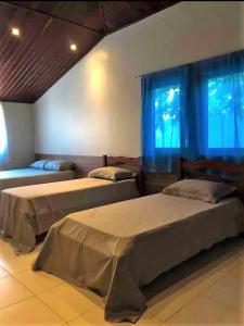 two beds in a room with blue curtains at Villa Patara in Marechal Deodoro
