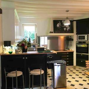 eine Küche mit einer Theke und 2 Hockern in der Unterkunft Maison spacieuse près de Vienne-en-Arthies avec jardin in Vienne-en-Arthies