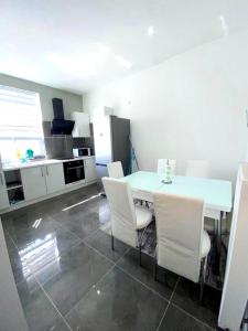 a kitchen with a white table and white chairs at One bedroom appartement with wifi at Anderlecht in Brussels