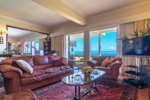 een woonkamer met een leren bank en een tafel bij Villa Amelia in Falésia by the Sea in Caniço