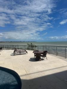 a patio with benches and a table and the ocean at Apartamento beira mar in João Pessoa