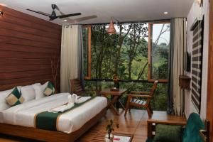 a bedroom with a bed and a balcony with a view at TREE6 WAYANAD in Vythiri