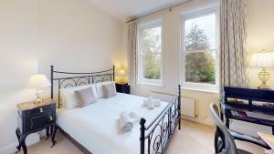 a bedroom with a black bed and two windows at Oxford Garden View in Oxford