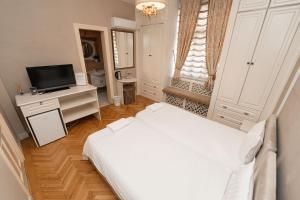 a white bedroom with a bed and a television at George&Dragon Rooms in Bucharest
