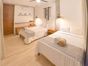 une chambre d'hôtel avec deux lits avec des serviettes dessus dans l'établissement Villa Toh, à Tulum