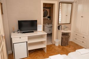 a living room with a television on a white desk at George&Dragon Rooms in Bucharest