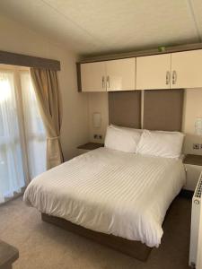 a bedroom with a large white bed and a window at 2 Bed, 2 Bath Lodge Style Caravan with Hot Tub & Private Garden at Patrington Haven Leisure Park in Patrington