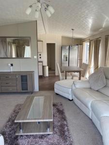 a living room with a white couch and a table at 2 Bed, 2 Bath Lodge Style Caravan with Hot Tub & Private Garden in Patrington