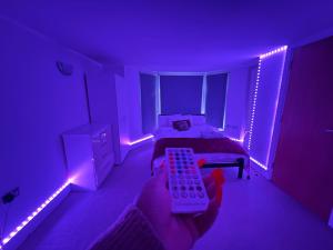 a purple room with a bed and a person holding a remote control at Serviced apartment in Kensington London Victoria in London