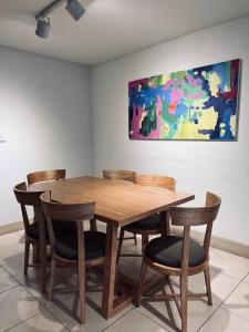 a wooden table with chairs and a painting on the wall at Amplio Dpto. con Balcón y cochera cerca del Parque in Mendoza