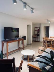 a living room with a tv and a couch and a table at Amplio Dpto. con Balcón y cochera cerca del Parque in Mendoza