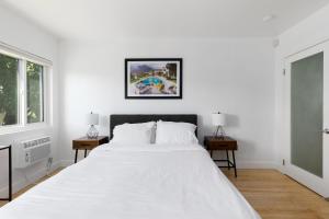 a white bedroom with a large white bed and two tables at Sunny Studio near Culver City in Los Angeles