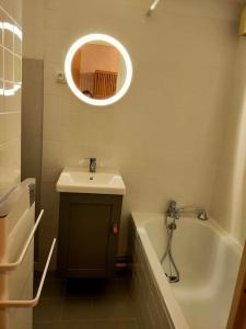 uma casa de banho com um lavatório, uma banheira e um espelho. em Le Seignus: superbe studio avec vue sur les pistes em Allos