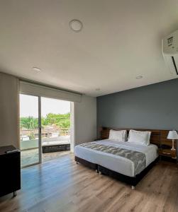 ein Schlafzimmer mit einem großen Bett und einem großen Fenster in der Unterkunft Malik Hotel Boutique in Cali