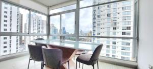 einen Tisch und Stühle in einem Zimmer mit großen Fenstern in der Unterkunft Splendid Apartment City Center - PH Quartier Atlapa in Panama-Stadt