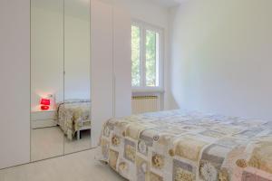 a white bedroom with a bed and a window at Appartamento Rupestre in Manerba del Garda