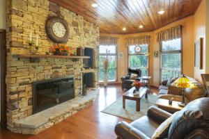 a living room with a stone fireplace with a clock at Beautiful Mountain Views and Privacy. Minutes to downtown Gatlinburg and National Park in Gatlinburg