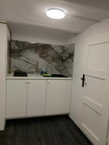uma cozinha com armários brancos e um lavatório num quarto em Madera House em Katowice