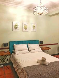 une chambre avec un grand lit et une tête de lit bleue dans l'établissement Cosy Bachelors, 2 min walk to Melville 7th, à Johannesbourg
