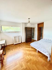 a white bedroom with a bed and a wooden floor at Appartamento nel verde fronte ospedale San Pietro, Sant'Andrea in Rome