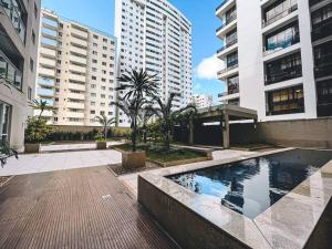 a pool in the middle of a city with tall buildings at Apartamento super agradável! Perto de tudo em Águas Claras in Brasilia