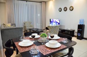 een woonkamer met een tafel, stoelen en een televisie bij Yohana Residences in Nairobi