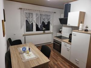 a kitchen with a wooden table and a kitchen with white appliances at Mara in Neuhaus an der Pegnitz