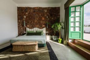 a bedroom with a bed and a brick wall at Hotel Cesar Lanzarote in La Asomada