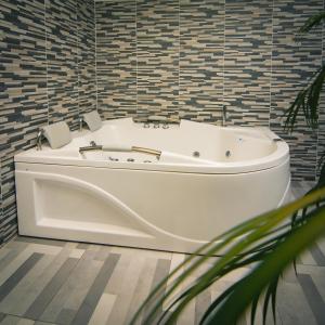 a white bath tub in a bathroom with tiles at Malik Hotel Boutique in Cali