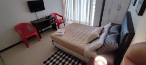 een kleine slaapkamer met een bed en een rode stoel bij Tranquilidad, Rincón Vivaldi in Vila El Carmen